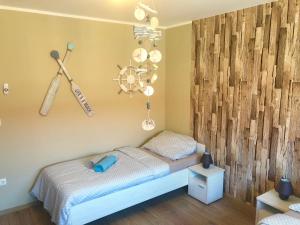ein Schlafzimmer mit einem Bett mit einer Holzwand in der Unterkunft Beachside Apartment in Szántód