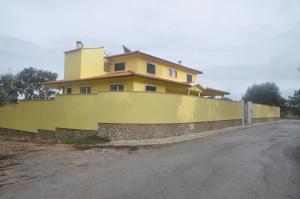 ein gelbes Haus auf einer Steinmauer in der Unterkunft O cantar dos passarinhos in Fátima