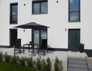 een patio met een tafel en stoelen en een parasol bij Ferienwohnung Selina-Sophie in Sehringen