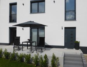 a patio with a table and chairs and an umbrella at Ferienwohnung Selina-Sophie in Sehringen +4 photos