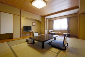 a living room with a table and a tv at Shiga Park Hotel in Yamanouchi