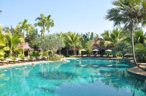a swimming pool at a resort with palm trees at Laluna Hotel And Resort, Chiang Rai in Chiang Rai
