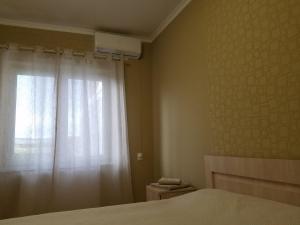 a bedroom with a bed and a window with a curtain at marini in Tbilisi City