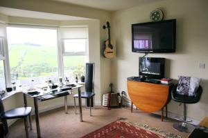 a room with a desk and a television and a table with a guitar at Wild Atlantic View Inishowen in Greencastle