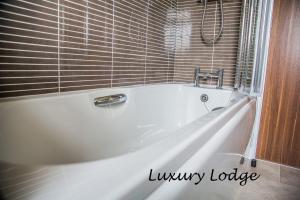 a white bath tub in a tiled bathroom at Inverbeg Holiday Park in Luss +29 photos