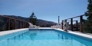 a swimming pool with two lawn chairs at Balcones de La Cumbrecita in La Cumbrecita