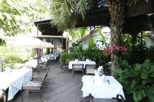 un restaurante con mesas y sillas blancas y un árbol en Laluna Hotel And Resort, Chiang Rai, en Chiang Rai