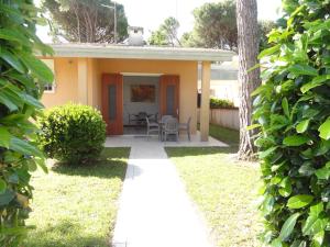 a small yellow house with a table and chairs at Villa Agavi 2 in Bibione