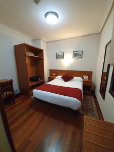 a bedroom with a bed with a red and white blanket at Pension Alameda in San Sebastián