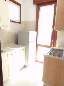 een keuken met een witte koelkast en een wastafel bij Villa Agavi 2 in Bibione