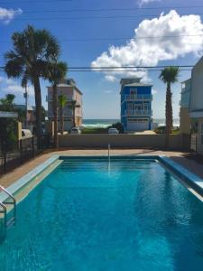 a large blue swimming pool with palm trees and a building at The Catalina in Panama City Beach