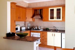 - une cuisine avec des placards en bois et un bol vert sur un comptoir dans l'établissement Best Located Apt - Fabulous Pool !, à Cabanas de Tavira