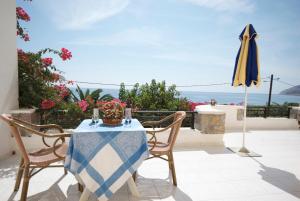 a table and chairs with an umbrella and the ocean at Sarikampos Beach in Myrtos