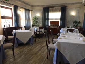 un restaurant avec tables et chaises et nappes blanches dans l'établissement Hotel Lugana Parco Al Lago, à Sirmione