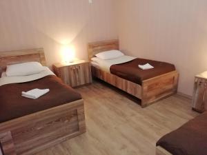 two twin beds in a room with wooden floors at Guest House ELENA in Kutaisi