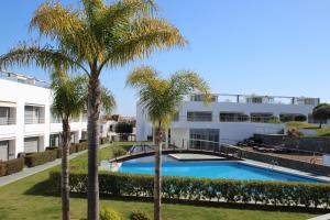 a pool with palm trees in front of a building at Penthouse in private complex by Homekeys in Tavira