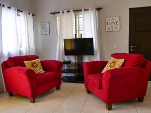 2 rote Stühle und ein TV im Wohnzimmer in der Unterkunft Playa Dorada Mountainview Villa in San Felipe de Puerto Plata