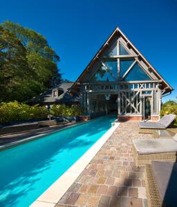 a large house with a swimming pool in front of a building at Hôtel La Licorne & Spa in Lyons-la-Forêt