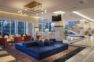 eine Lobby mit einem blauen Sofa und Stühlen sowie einem TV in der Unterkunft Horison Ciledug Jakarta in Jakarta