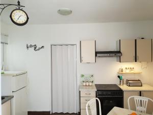 kuchnia z białymi szafkami i zegarem na ścianie w obiekcie Apartment Split w Splicie