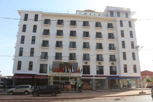 un bâtiment blanc dans une rue avec des voitures garées devant. dans l'établissement Bissau Royal Hotel, à Bissau