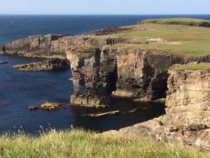 a view of a rocky cliff with the ocean at 8 Jib Park, Orkney Islands in Finstown