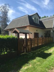 a house with a wooden fence and an umbrella at Van egy ház a Tisza parton in Tiszaderzs