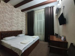Dormitorio pequeño con cama y TV en Hotel Anor, en Samarkand