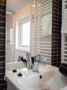 La salle de bains est pourvue d'un lavabo blanc et d'une fenêtre. dans l'établissement Luxe Lodge Zeehoeve, à Harlingen
