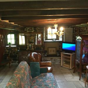 a living room with a couch and a tv at Lieu dit le jardin in Saint-Lambert