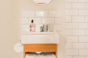 a white bathroom with a sink and a mirror at The Amberley Annex in Muizenberg +14 photos