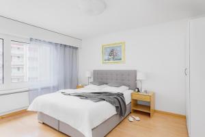 a white bedroom with a bed and a window at Swiss Star Zurich Oerlikon - Self Check-In in Zürich