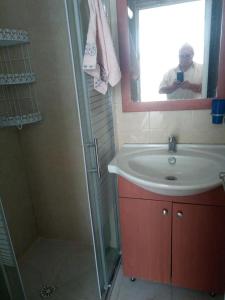 um homem tirando uma foto de uma casa de banho com um lavatório e chuveiro em Sheffer em Ramat Gan