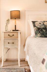 a bedside table with a lamp on it next to a bed at The Amberley Annex in Muizenberg