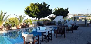 um pátio com mesas e cadeiras ao lado de uma piscina em Villa Koronios em Fira