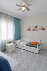 a bedroom with two beds and a ceiling fan at Chalkidiki Beachfront Apartment in Nea Iraklia
