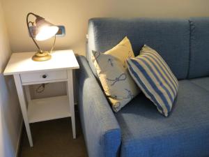 Un sofá azul con almohadas y una lámpara en una mesa lateral. en La Vignana - 5 Terre, en Levanto