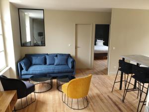 a living room with a blue couch and chairs at Au Loup Historic Apartments in Bayeux