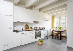 a kitchen with white cabinets and a dining table at Swiss Star District 11 - Self Check-In in Zürich