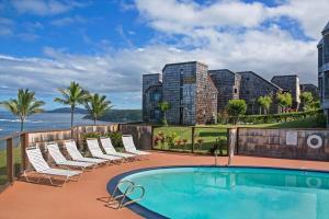 a swimming pool on a balcony with chairs and the ocean at Sealodge H9 Condo in Princeville