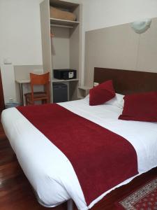 a bedroom with a large white bed with red pillows at Pension Alameda in San Sebastián