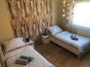 a bedroom with two beds and a wooden wall at Beachside Apartment in Szántód