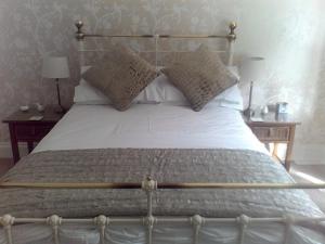 1 dormitorio con 1 cama grande con sábanas y almohadas blancas en Baytree B&B en Charlestown