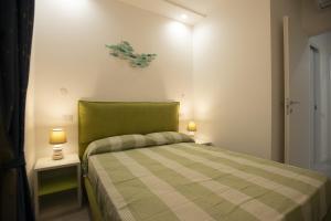 a small bedroom with a green bed with two lamps at Appartamento Roberto House in Fertilia
