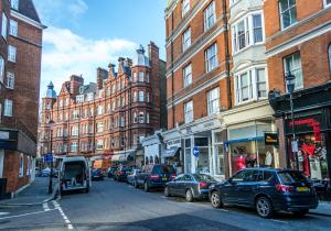 uma movimentada rua da cidade com carros estacionados na rua em One bedroom High street kensington Apartment em Londres