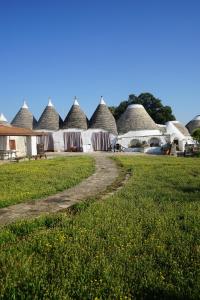 a row of thatched huts with a dirt road at Masseria Ferri in Ostuni