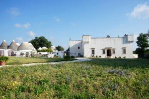 a white house with a field of grass and flowers at Masseria Ferri in Ostuni