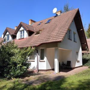 ein weißes Haus mit einem roten Dach und einem Hof in der Unterkunft Mandarynkowy in Dębki