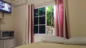 una camera da letto con finestra e tende rosse di Yard Style a Kingston