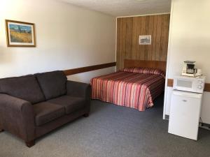 Habitación de hotel con sofá y cama en Yellow Quill Motel en Portage La Prairie